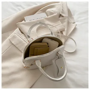 Interior capacity detail of white shell handbag with mustard wallet and phone