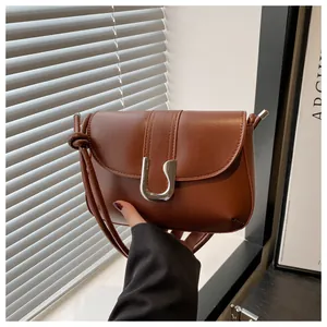 Detail of caramel brown leather handbag with silver U-shaped metal buckle and knotted strap
