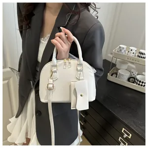 Detailed view of a white shell handbag with a detachable small pouch and golden zippers