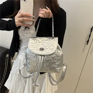 Silberner Mini-Rucksack mit herzförmiger Steppung und Metallic-Finish am Modell