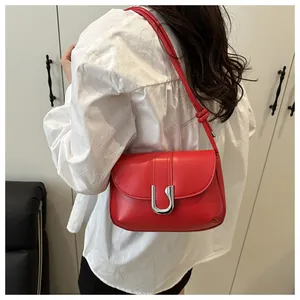 Detail of red leather shoulder bag showing the silver U-shaped metal lock and knot strap