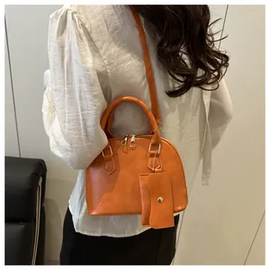 Orange shell-shaped handbag with matching mini pouch accessory shown on a model
