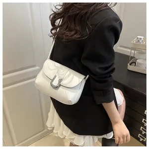 Detailed close-up of white leather handbag with U-shaped silver buckle and fine stitching