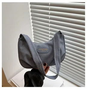 Detail of grey pleated crescent hobo bag with sleek brand plate and woven texture