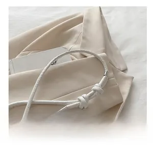 Detail of white embossed leather shoulder strap with decorative knots and silver metal caps