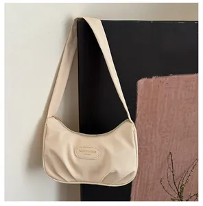 Detailed view of the off-white canvas shoulder bag with pleated base and leather logo patch