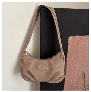 Close-up of brown canvas hobo bag showing pleated texture and golden zipper detail