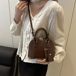 Deep brown retro shell bag with top handles, adjustable strap and mini charm