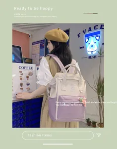 Detail of a beige and lilac canvas backpack with strawberry charm in a cozy cafe setting