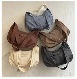 Texture detail of five pleated corduroy handbags in blue, red, brown, beige, and grey