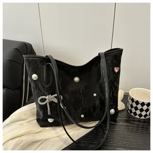 Detail of black tote bag with pearl accents and a crystal bow charm on wrinkled fabric
