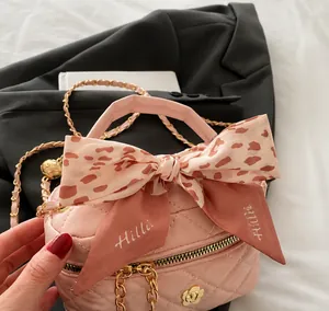 Close-up of pink quilted mini bag with leopard print silk bow and golden chain strap