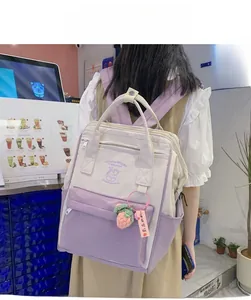 Detail view of purple and beige patchwork backpack with cute strawberry charm accessory