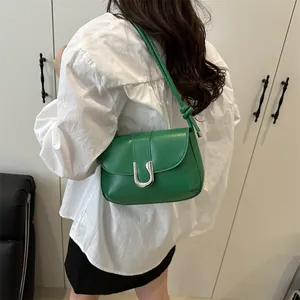 Chic green leather shoulder bag with U-shaped buckle and knotted strap on female model
