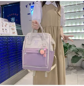 Detail view of a dual-tone nylon backpack in cream and lilac with a strawberry charm