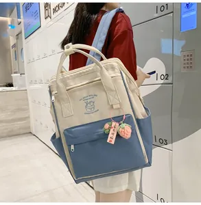 Detail of a lightweight beige and blue backpack with a strawberry charm on a side pocket