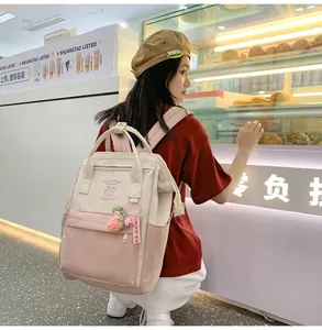 Detail view of pink and beige mini backpack with strawberry charm shown on model