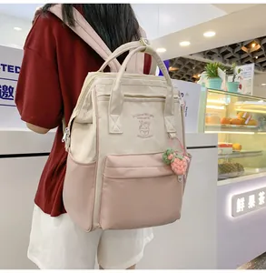 Detailed view of water-resistant beige and pink mini backpack with cute strawberry pendant