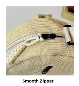 Detailed close-up of smooth zipper with woven knot puller on beige corduroy bag