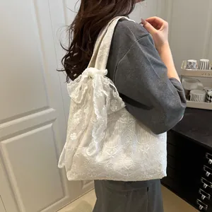 Detailed side view of off-white lace tote bag with floral patterns and a bow