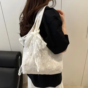Detail of white lace tote bag with vintage floral embroidery and large bow decoration