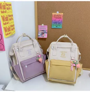 Detail of color-block canvas backpacks with cute strawberry charms and cartoon prints