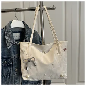 Detail of off-white tote bag featuring elegant pearls, bow knot and pink heart gemstone
