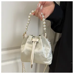 Detailed view of satin bucket bag with floral embroidery and elegant pearl handle