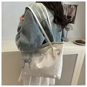 Detail view of tote bag with pearls, silver bow charm, and heart crystal decoration