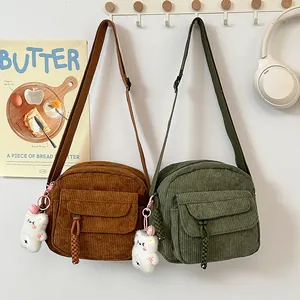 Detail of corduroy crossbody bags in brown and green with cute plush bear charms