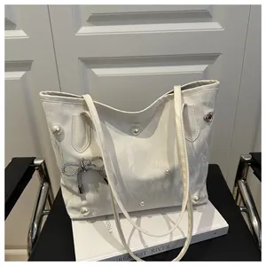 Detail of white marble tote bag with pearl accents and a diamond bow pendant