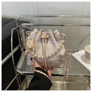Detail of floral jacquard bucket bag with pearl handle and metal chain strap