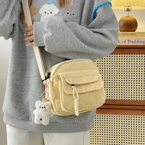 Detail of yellow corduroy crossbody bag with cute plush bear charm and wide strap