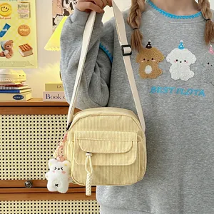 Detail of yellow corduroy crossbody bag with cute plush bear and cream canvas strap