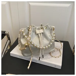 Close-up of champagne bucket bag with floral embroidery and pearl handle detail