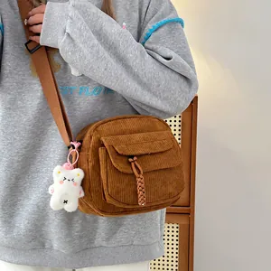 Brown corduroy crossbody bag detail with front pocket and cute white plush bear charm