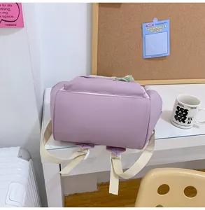 Detail view of purple nylon backpack base and adjustable cream strap in a cozy desk setting