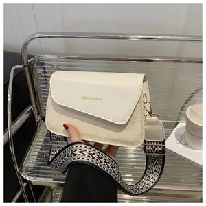 Detail of crossbody bag with beige woven texture, leather flap and geometric wide strap