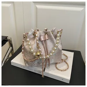 Detail of pink satin bucket bag featuring floral embroidery and pearl handle