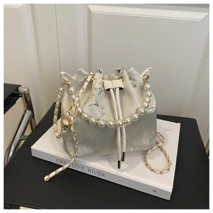Detail of silk bucket bag with lotus embroidery, pearl handle and gold chain strap