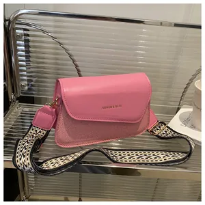 Detail of pink leather flap bag with woven texture and geometric patterned wide strap