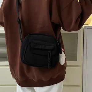 Fashionable black corduroy crossbody bag with a cute white plush kitten charm