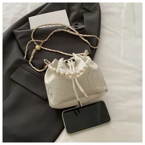Detailed close-up of pearl handle and bamboo pattern on a white satin bucket bag