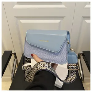 Detail of light blue crossbody bag featuring mixed textures and geometric wide strap