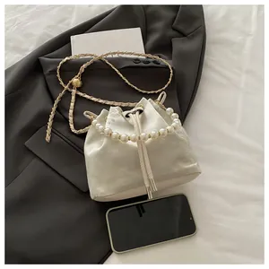Detailed view of white floral embroidery on bucket bag with pearl handle and chain strap