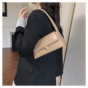 Minimalistische kaki leren baguette tas met gouden sluiting gedragen door model