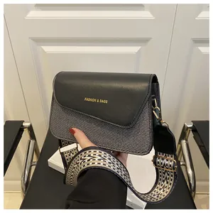 Detail of crossbody bag featuring woven texture, wide strap and gold fashion logo