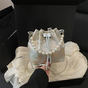 Blue brocade bucket bag with traditional embroidery, pearl handle, and chain strap
