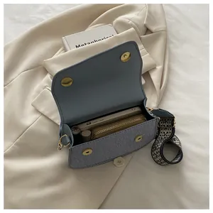 Detail of light blue crossbody bag with woven strap showing interior storage capacity