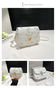 Détail du sac bandoulière blanc avec broderie florale et fermoir fer à cheval doré